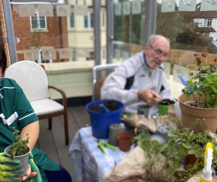 three elderly women engaging in a craft activity with lavender and fabric materials while enjoying a sunny outdoor setting related to relaxation and creativity